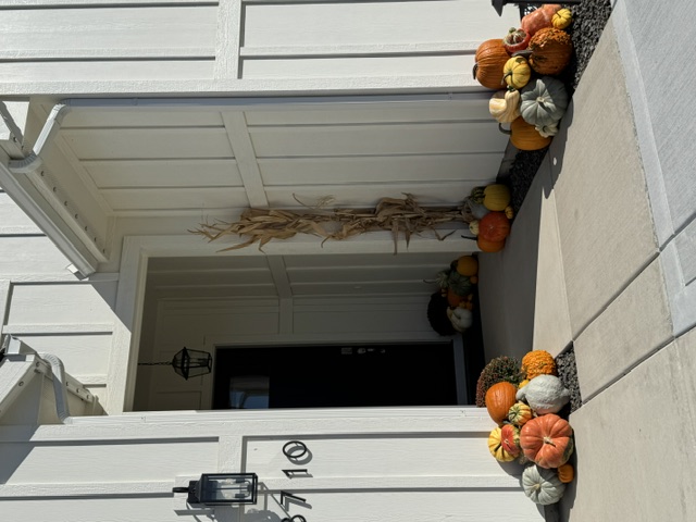 White porch decorated with a cart full of pumpkins and gourds