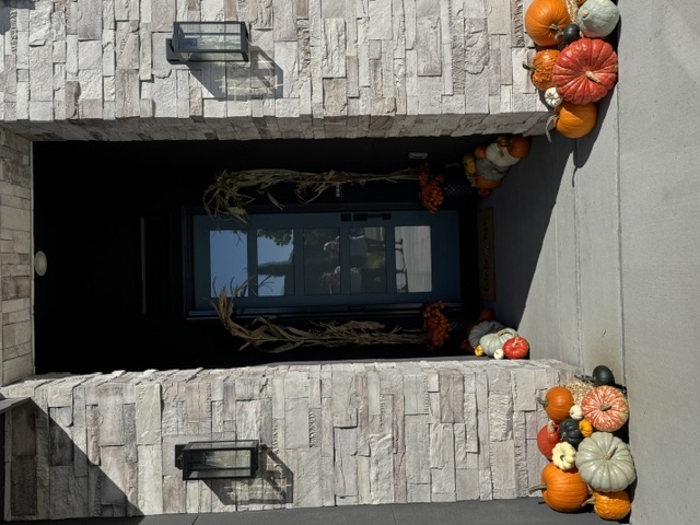Porch with white planters of purple mums and pumpkins on the steps
